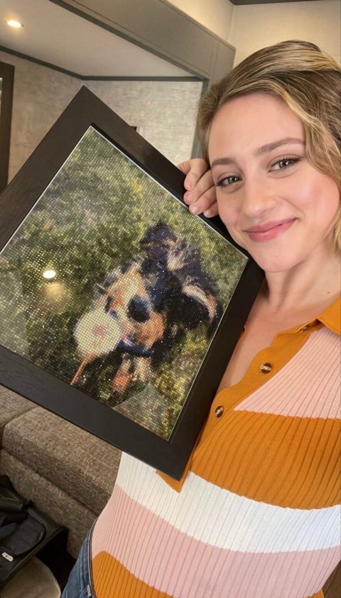 a woman holding up a framed photo of a dog