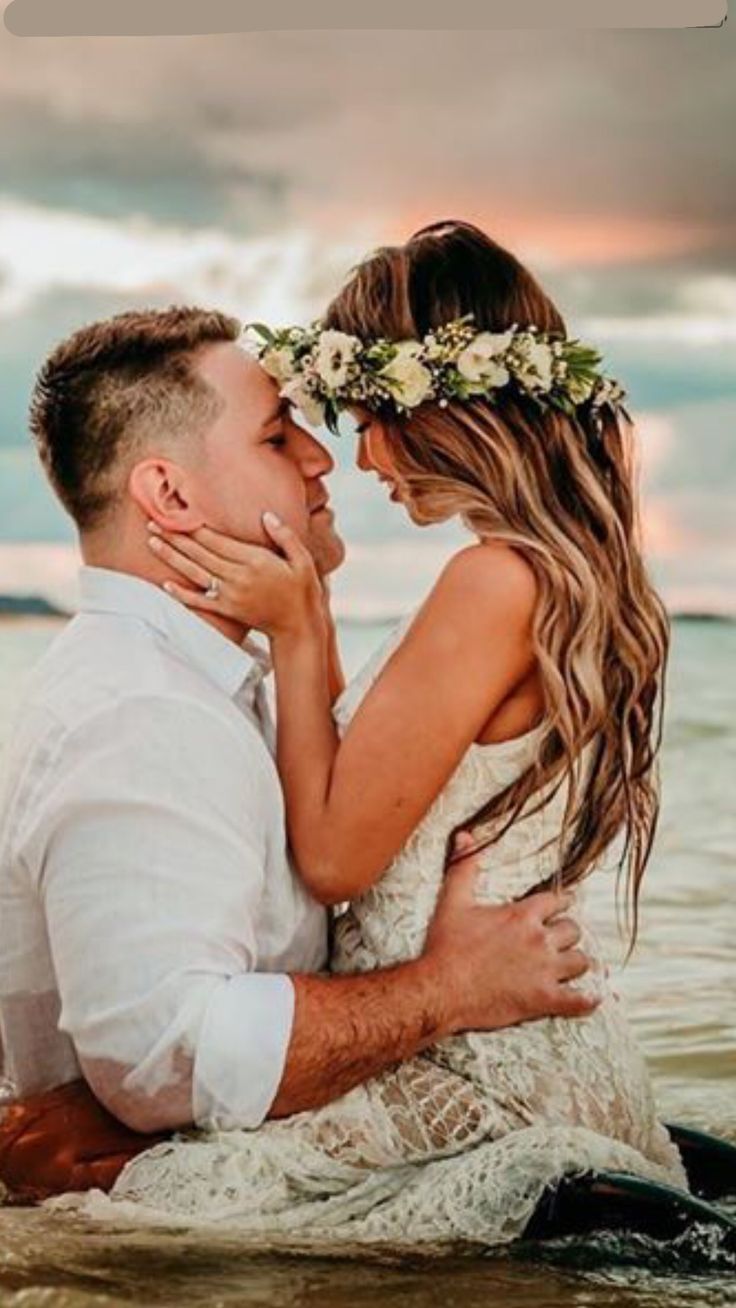 a man and woman are sitting in the water with their arms around each other as they look at each other