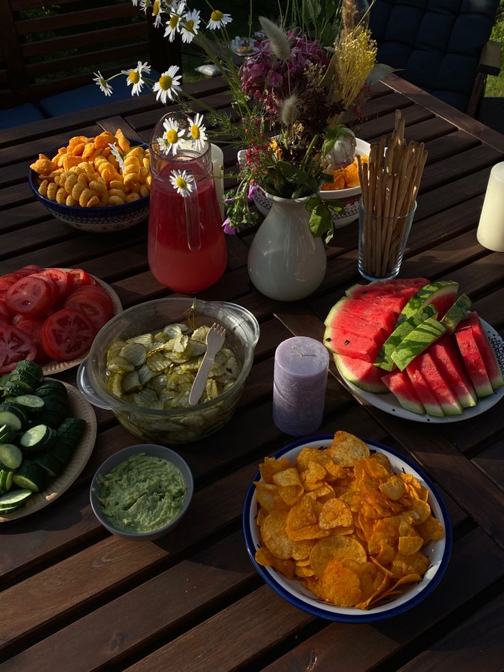 a table topped with plates of food and bowls of dips next to watermelon slices