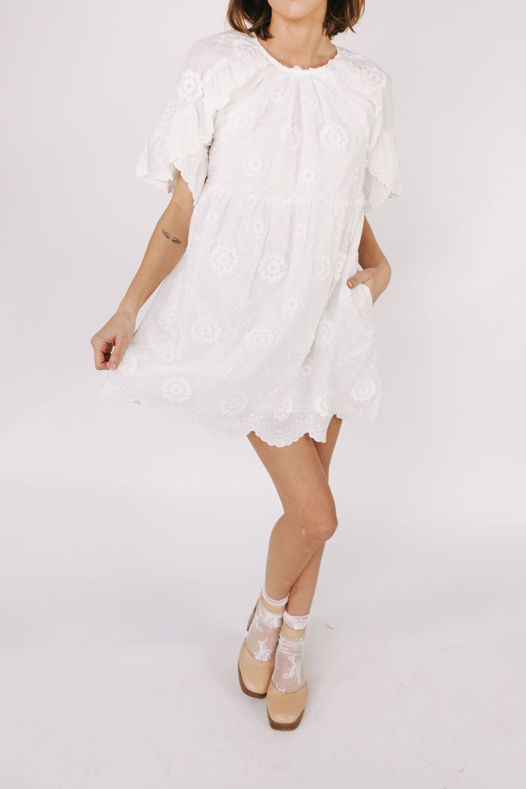 This white embroidered floral mini dress is the epitome of romantic elegance. Featuring a delicate scallop hemline and ruffle lace details, it is the perfect addition to any summer wardrobe. Enhance your feminine charm and steal hearts wherever you go with this beautiful dress. Details Round neckline Keyhole closure Ruffle lace details Embroidered fabricaiton Scallop hemline Lined Pockets Sizing Approximate measurements: SIZE LENGTH BUST WAIST Small 33” 36” 36” Medium 33” 38” 38” Large 34” 40” 40” Fabric has no stretch Model is 5’8” wearing small Material Self: 85% Tencel 15% NylonLining: 97% Polyester 3% Spandex Hand wash cold cold Do not bleachLay flat to dryFor best results dry clean Flowy Lace Dresses With Floral Embroidery, Spring Crochet Mini Dress With Lace Trim, Spring Crochet Dress With Lace Trim, Feminine Lace Trim Mini Dress, Feminine Scalloped Lace Mini Dress, Summer Brunch Dresses With Scalloped Edges, Flowy Lace Dress With Lace Trim For Garden Party, Feminine Spring Mini Dress With Scalloped Edges, Daywear Mini Dress With Scalloped Lace