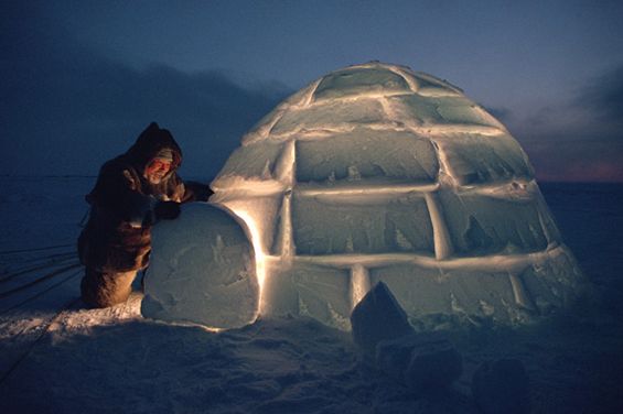 an igloose is lit up with lights and snow as it sits on the ground