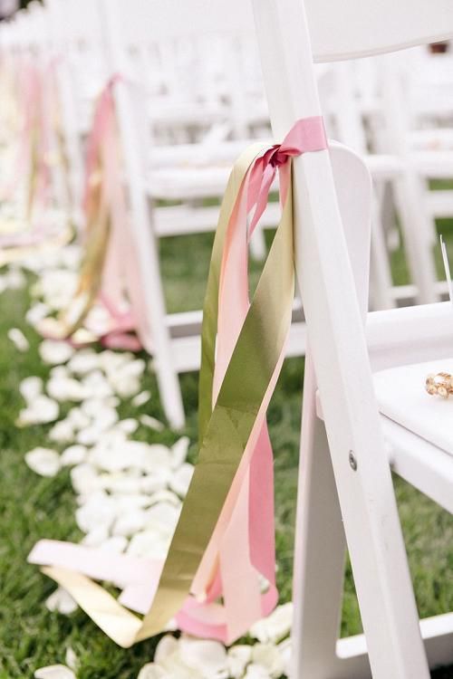 the wedding aisle is decorated with pink and gold ribbons