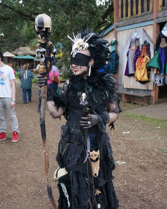 a man dressed in costume holding a stick and wearing a mask with feathers on it