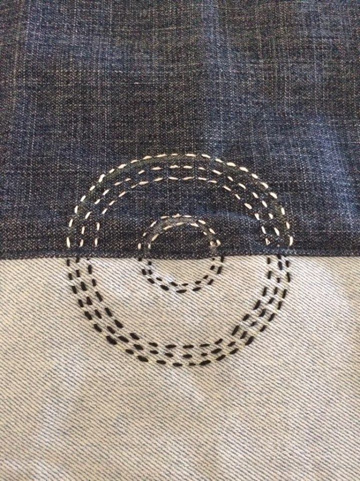 the back side of a pair of jeans with an embroidered circle on it and stitching