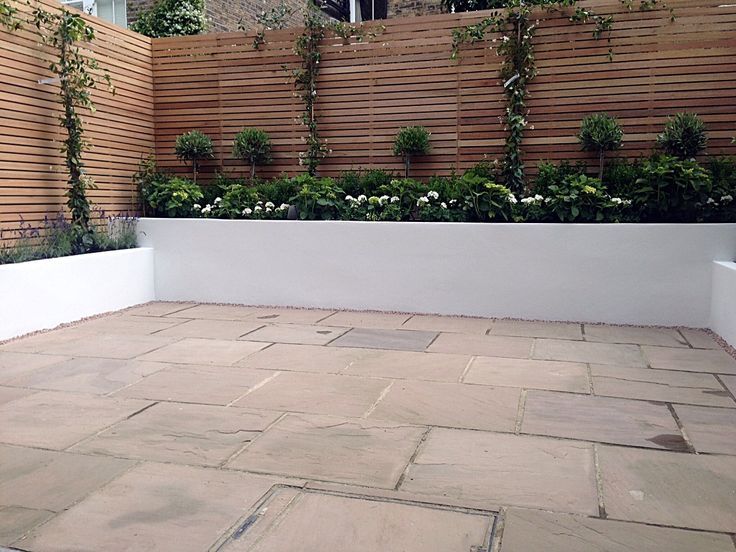 an outdoor patio with white planters and flowers