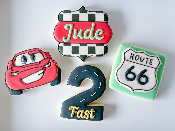 three decorated cookies with the number two and cars on them are sitting next to each other