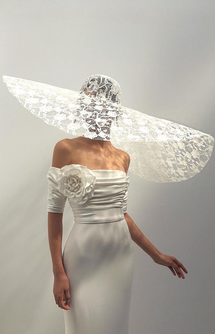 a woman in a white dress with wings on her head and veil over her face