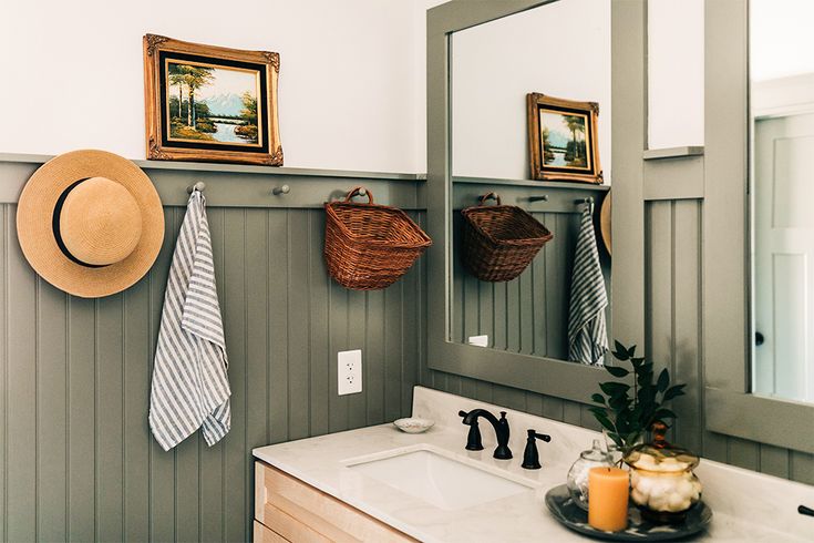 a bathroom with green walls and white counter tops, two pictures hanging on the wall