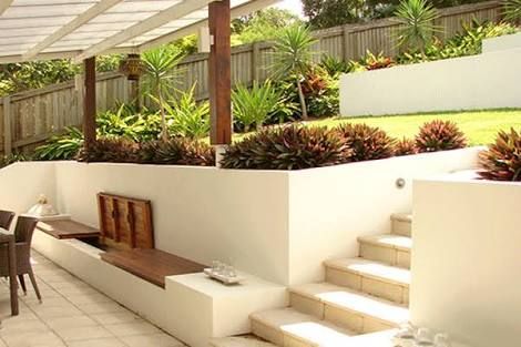 an outdoor dining area with white walls and tiled flooring, surrounded by greenery