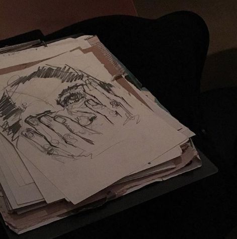 a stack of papers with drawings on them sitting on a chair in front of a wall