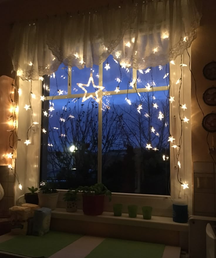 the window is decorated with christmas lights and stars on it's curtained windowsill