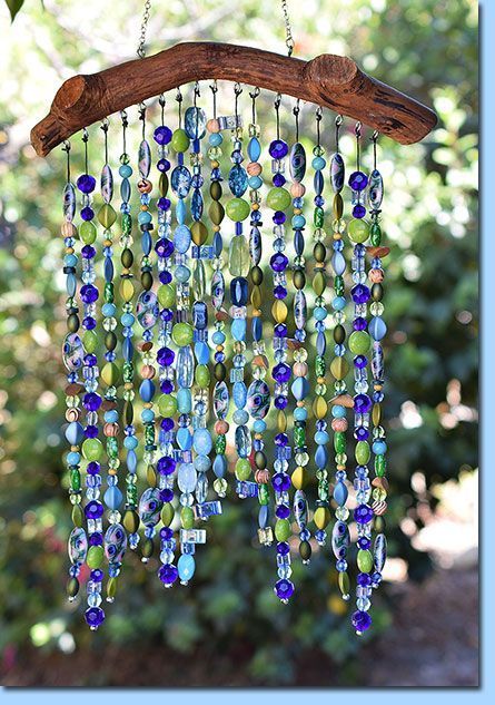 a wind chime hanging from a tree branch with lots of glass beads on it