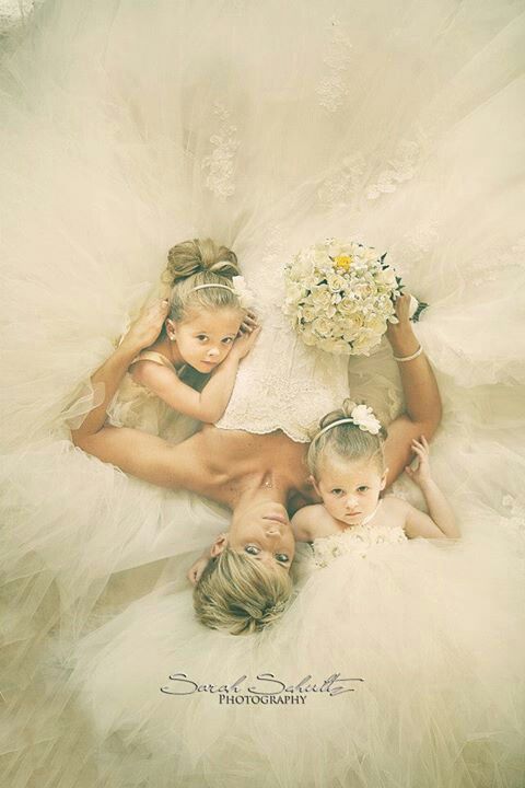 three women and two children laying on the floor in white dresses with tulle skirts