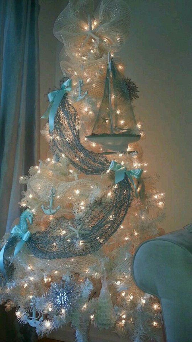 a white christmas tree with blue bows and lights