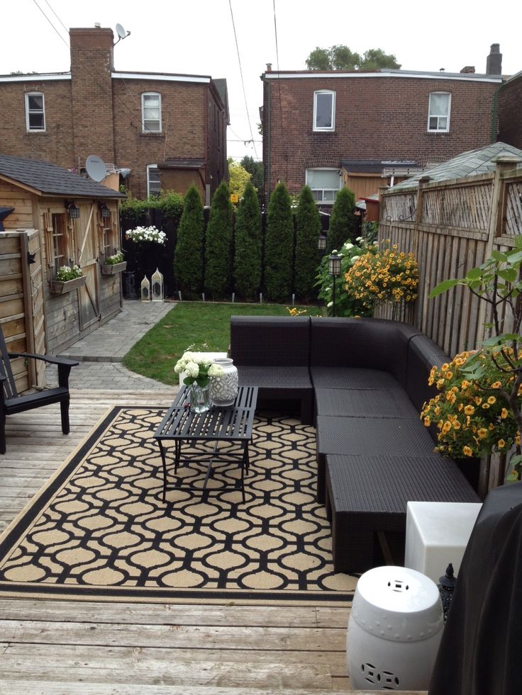 an outdoor living area with couches, tables and flowers on the deck in front of houses