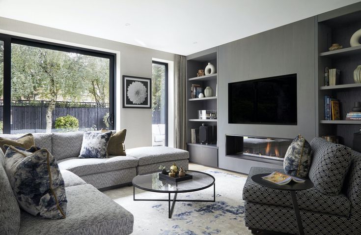 a living room filled with furniture and a flat screen tv mounted on a wall above a fire place