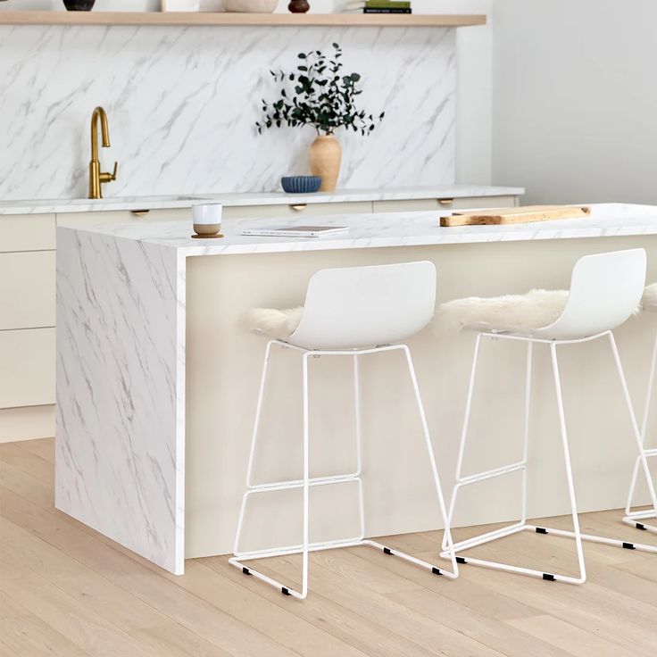 two white stools sit at the bar in this modern kitchen