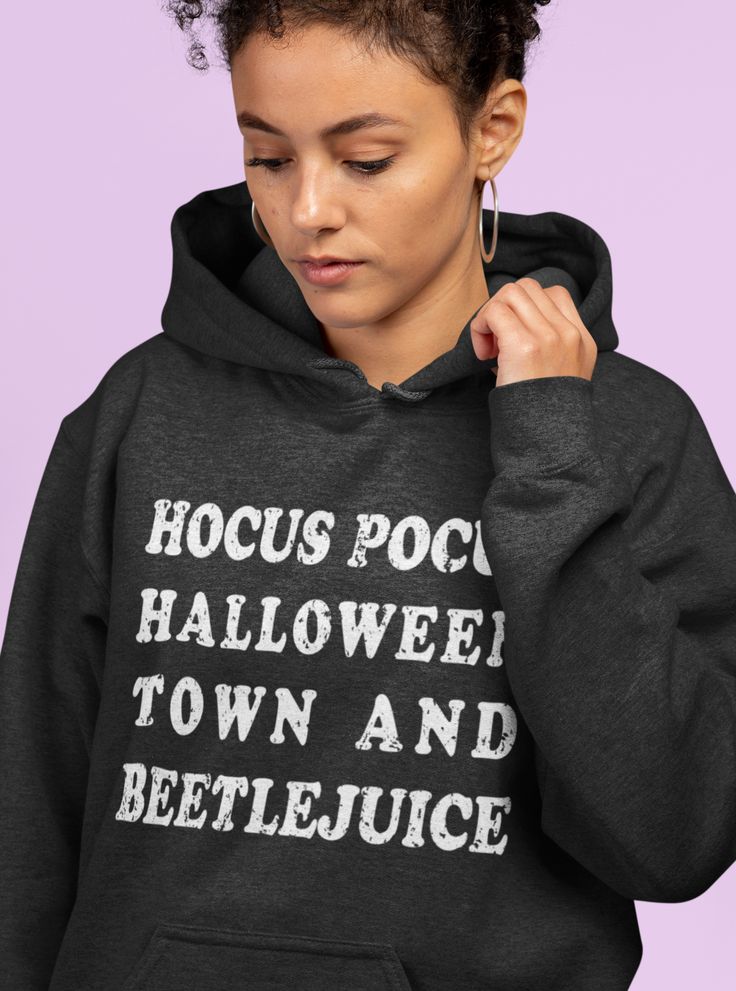 a woman wearing a black hoodie that says hoccus poo halloween town and beetlejuice