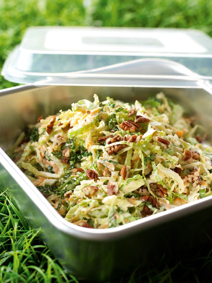 a metal pan filled with food sitting on top of green grass next to a plastic container