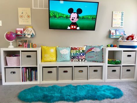 a child's bedroom with mickey mouse on the tv and toys in bins