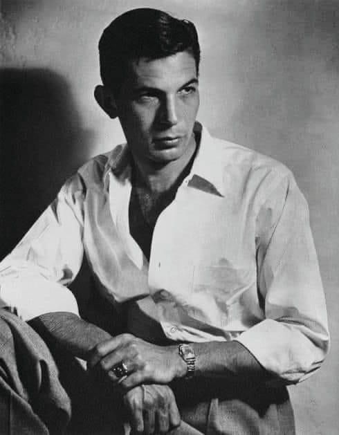 black and white photograph of a man sitting in a chair with his hands on his knees