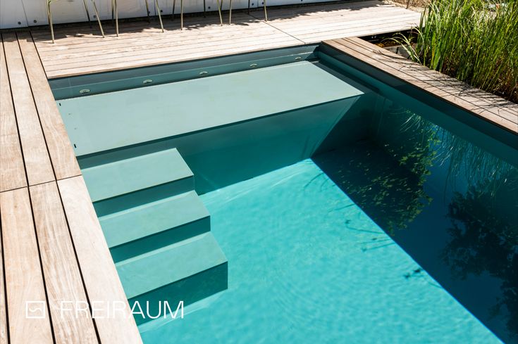 an empty swimming pool with steps leading up to the water's edge and grass growing on either side