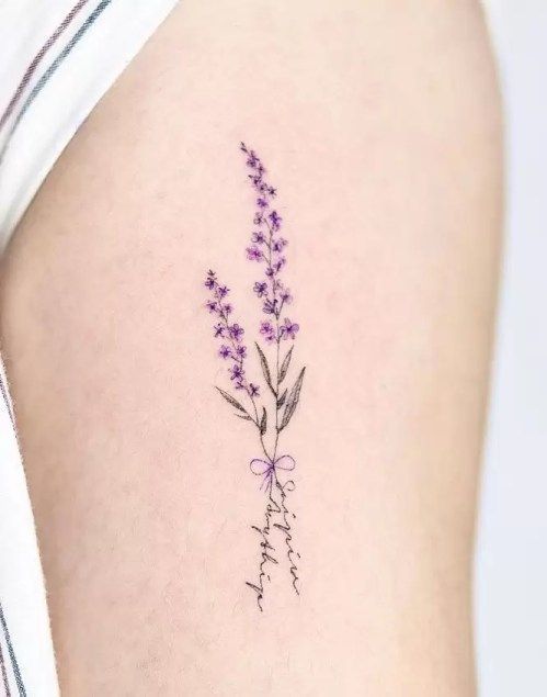 a small lavender tattoo on the back of a woman's left thigh, with flowers growing out of it