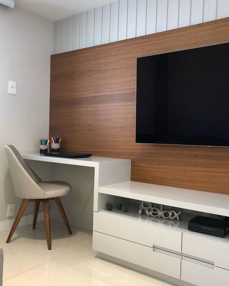 a flat screen tv mounted to the side of a wall next to a white desk