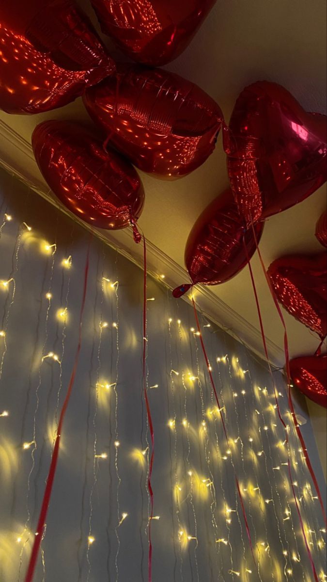 red heart shaped balloons hanging from the ceiling with string lights on them and streamers attached to the ceiling