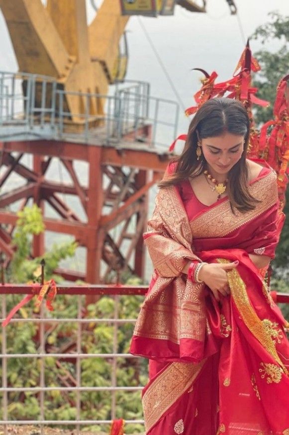 a woman wearing a red and gold sari