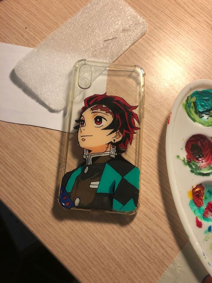 a phone case with an anime character painted on it next to some paintbrushes