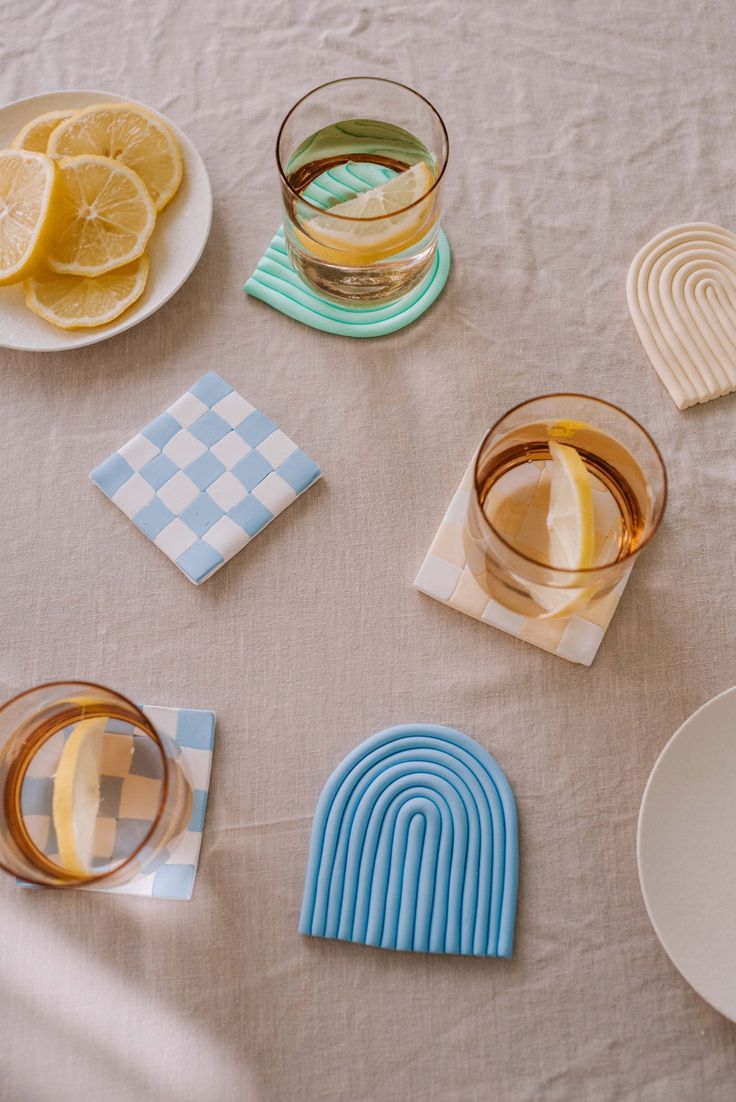 there are several glasses and plates on the table with lemons, gingham paper napkins, and coasters