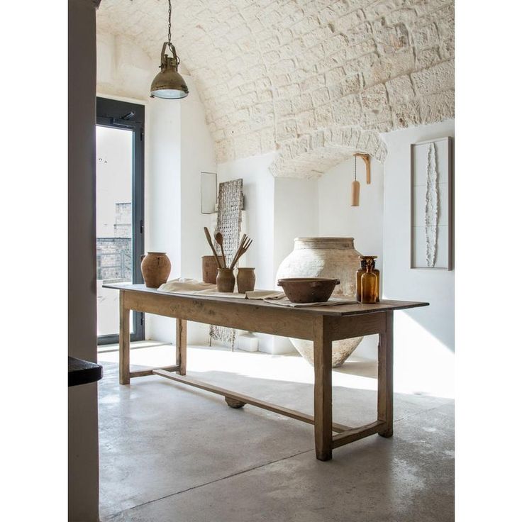 a table with two vases on it in front of an open door and window