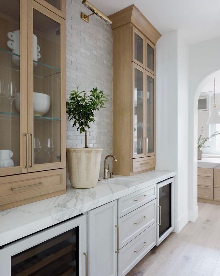 a kitchen with white counter tops and wooden cabinets, along with a potted plant