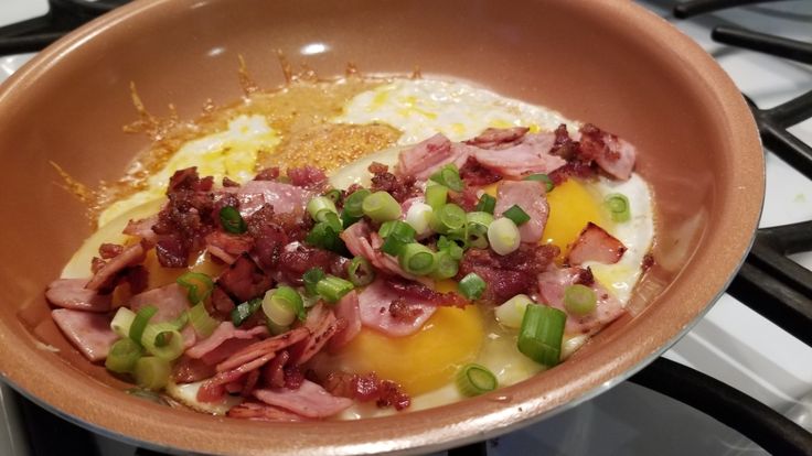 eggs, ham and green onions in a bowl on the stove