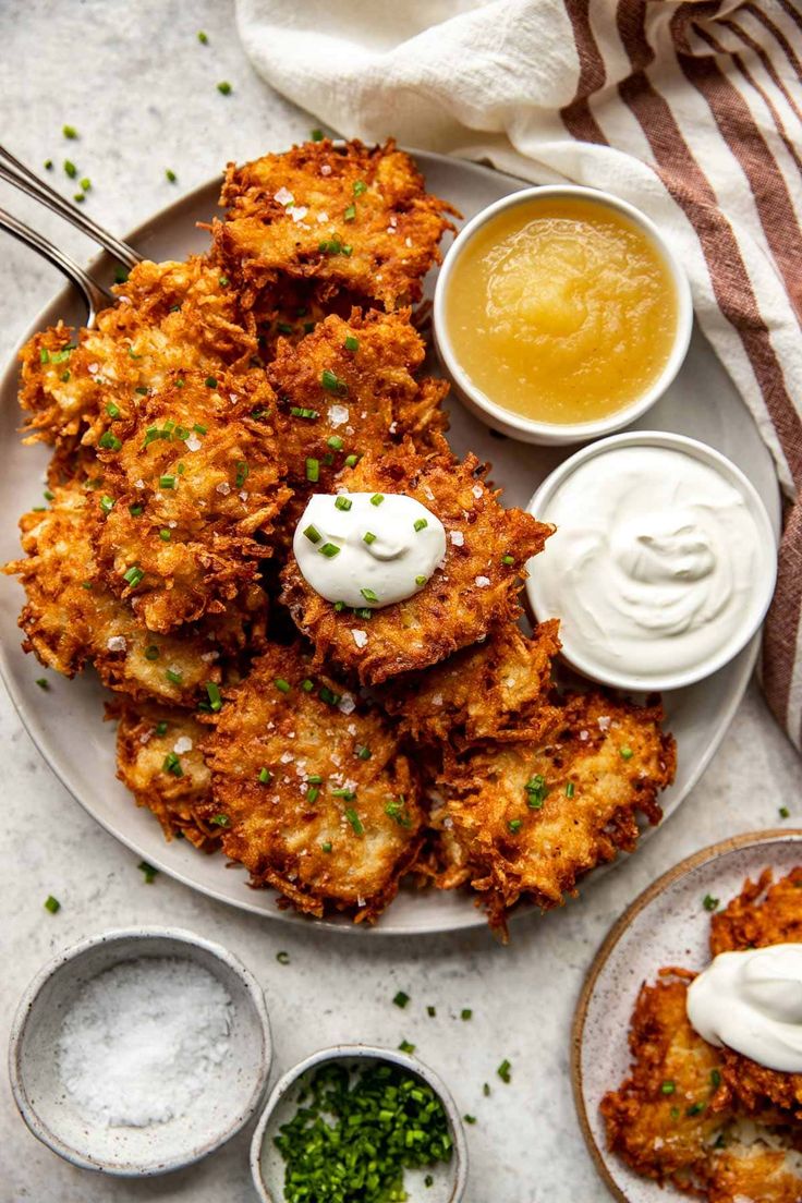 an overhead view of some fried food on a plate with sour cream and sauces