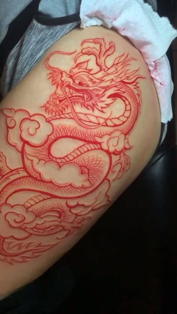 a red dragon tattoo on the back of a woman's thigh