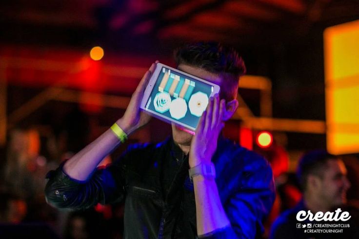 a young man holding up an electronic device to his face in front of the camera