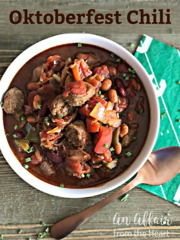 a white bowl filled with meat and beans on top of a green napkin next to a spoon