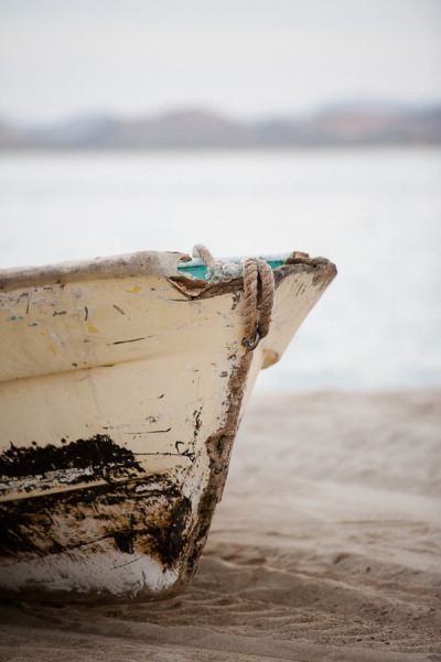 a boat sitting on top of a sandy beach