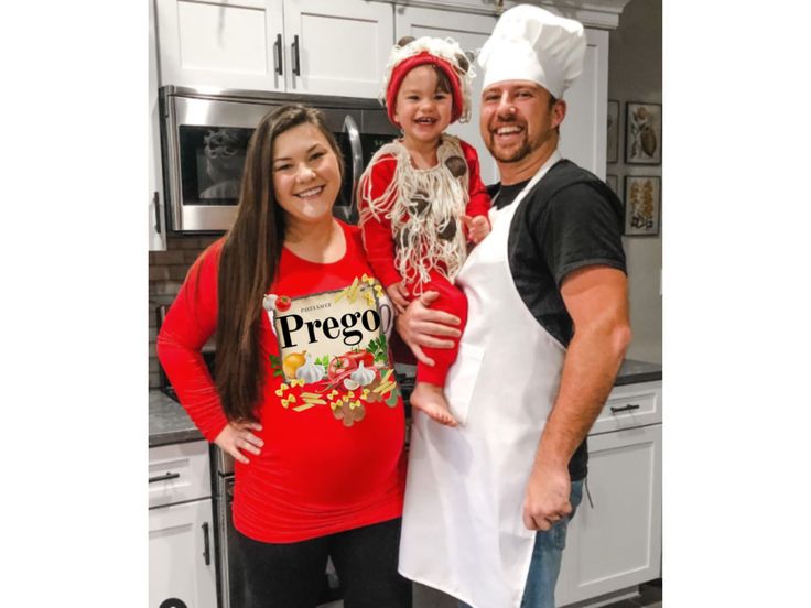 a man and two women are posing for a photo in the kitchen with a baby