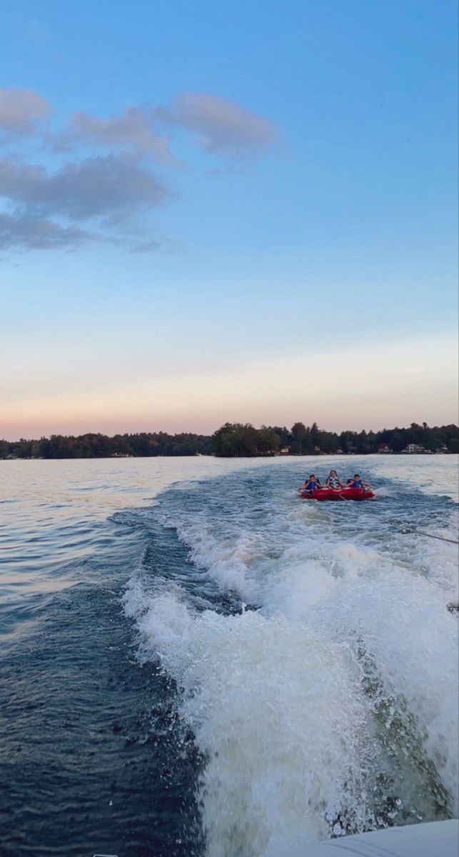 a boat with people riding on the back of it in the water at sunset or dawn