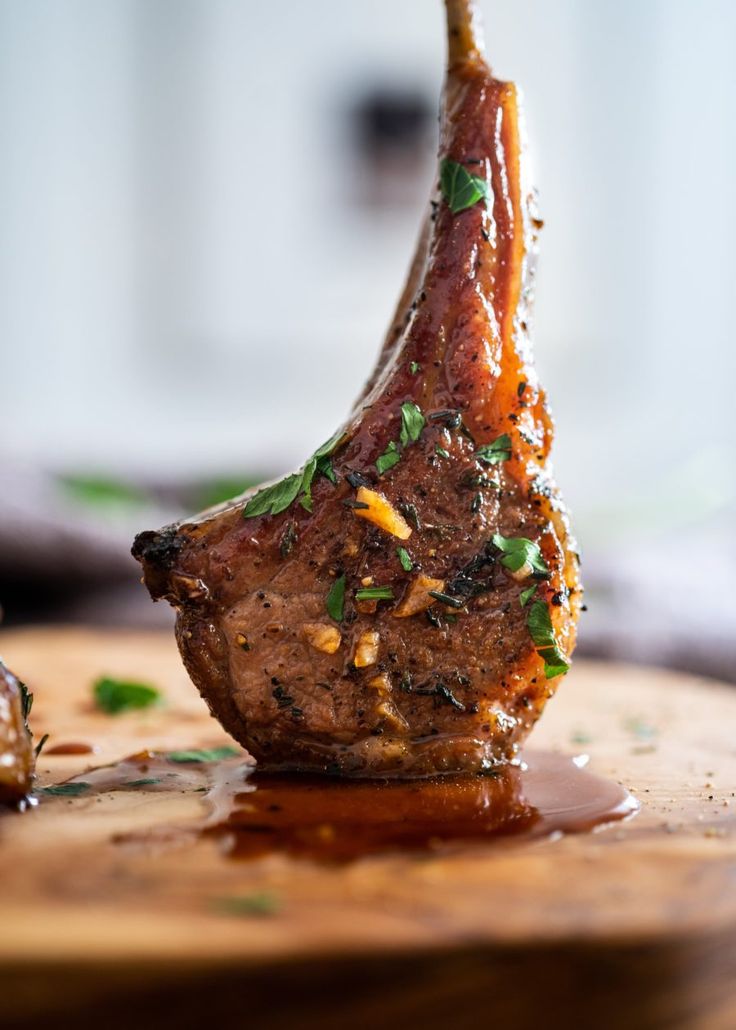 a piece of meat on a wooden cutting board with sauce and parsley sprinkled around it