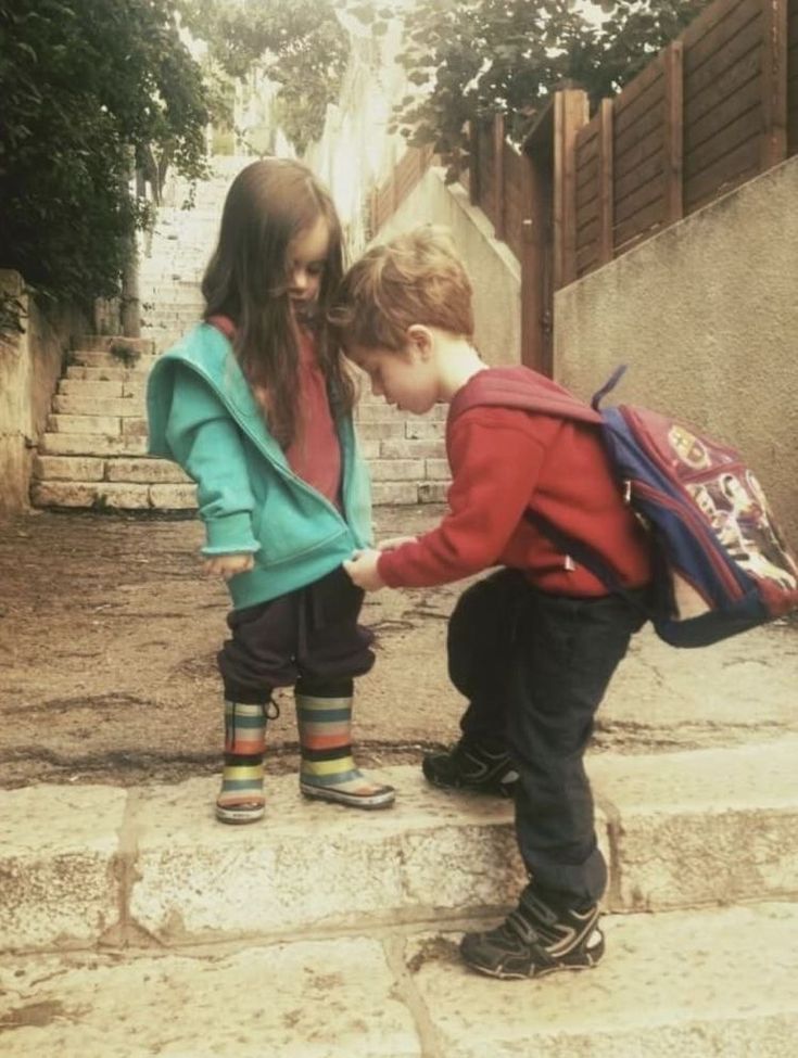 two young children playing with each other on steps