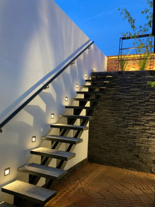 a set of stairs leading up to the top of a building with lights on them