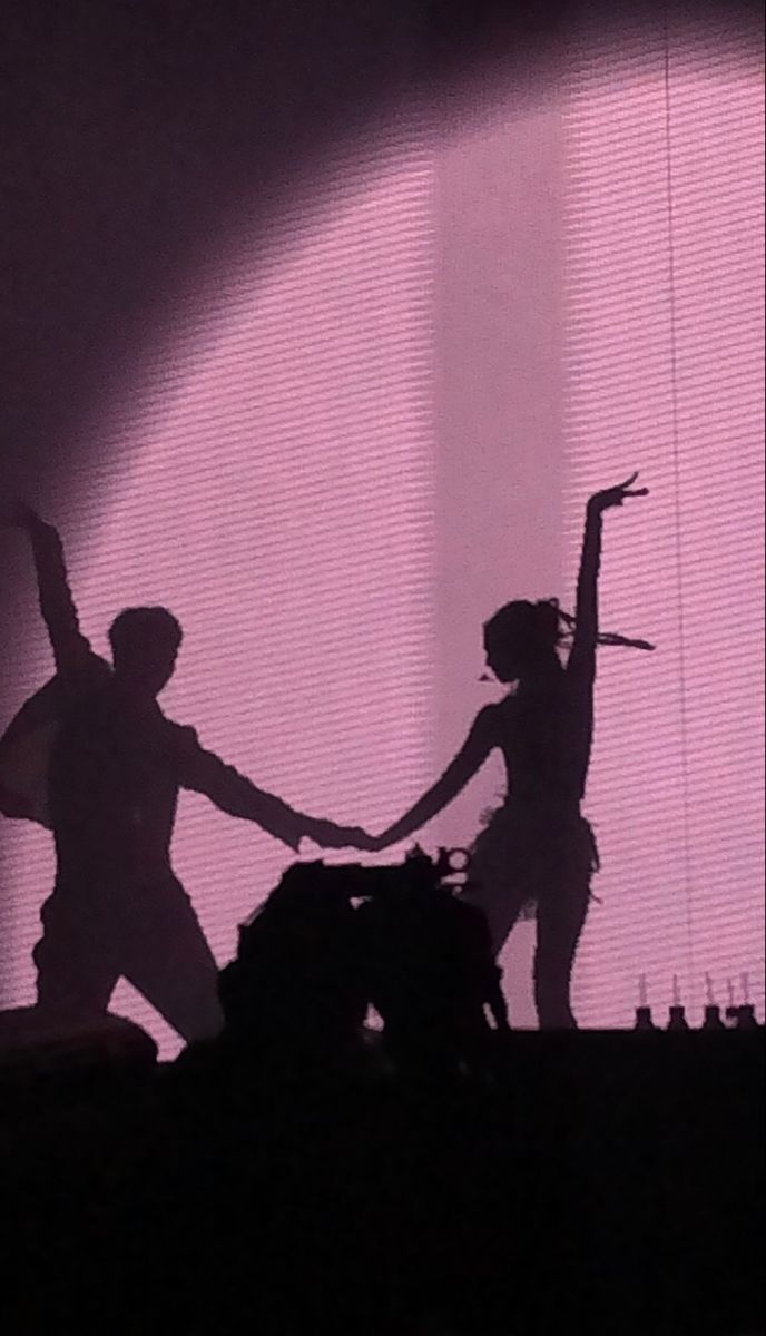 two people are dancing on stage with their arms in the air and one person is holding his arm out