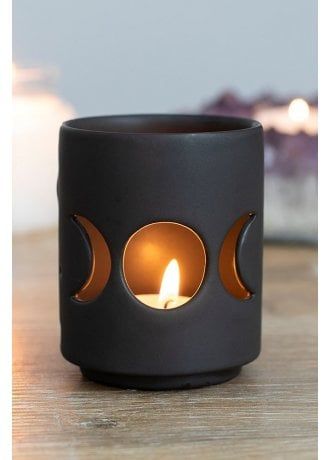 a small black candle holder with two candles in the shape of moon's eyes