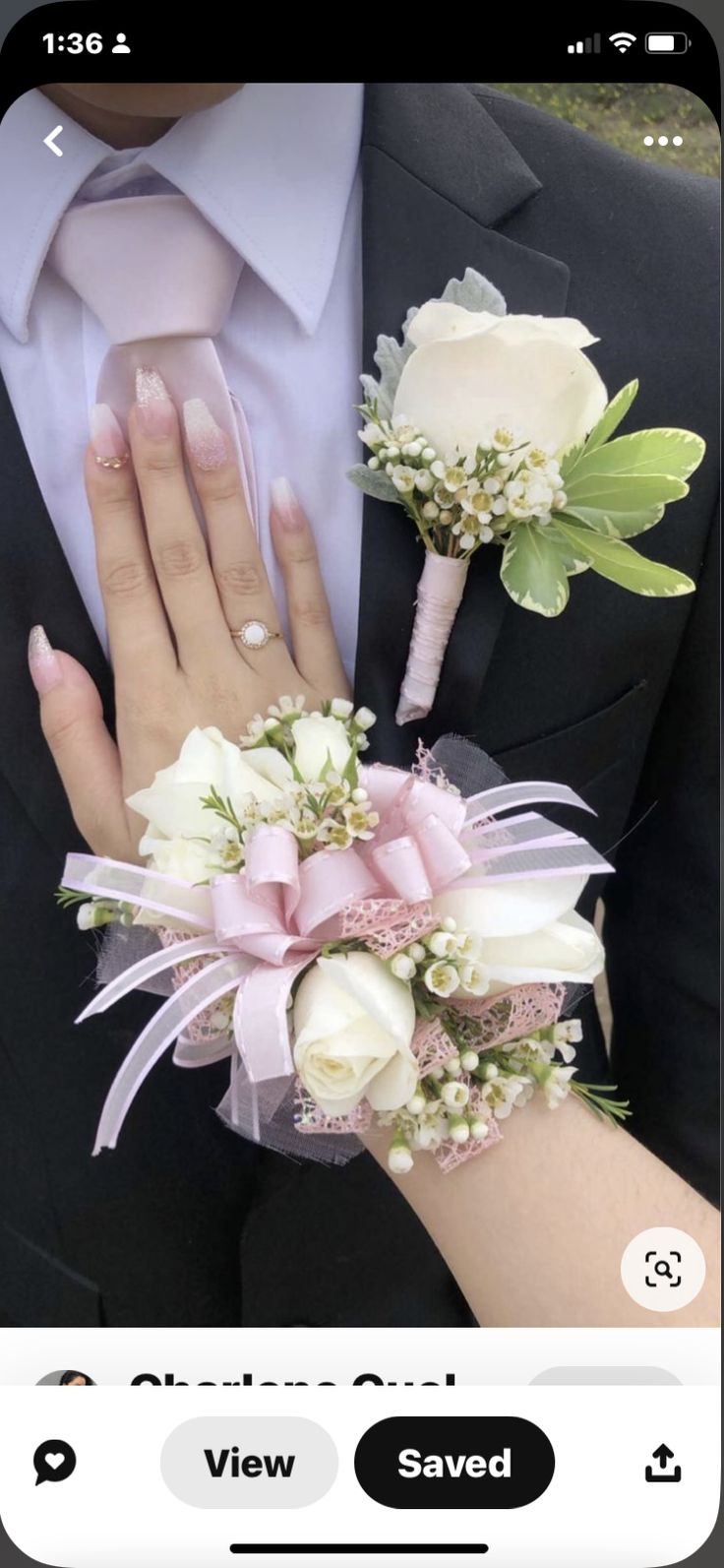 a person in a suit and tie with flowers on their wrist holding a ring bearer