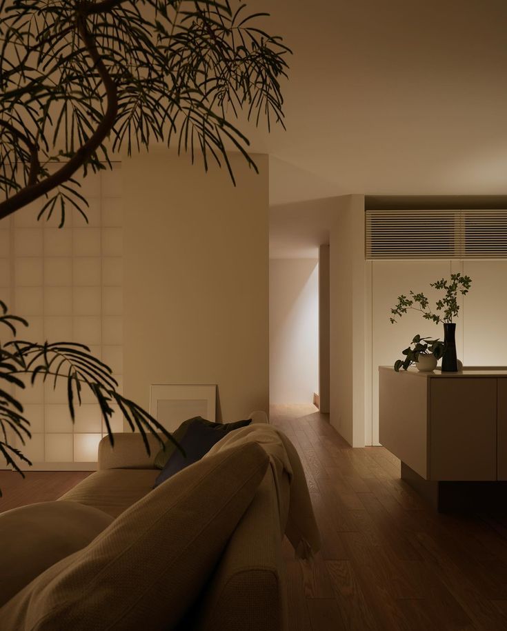 a living room filled with furniture next to a plant on top of a wooden floor