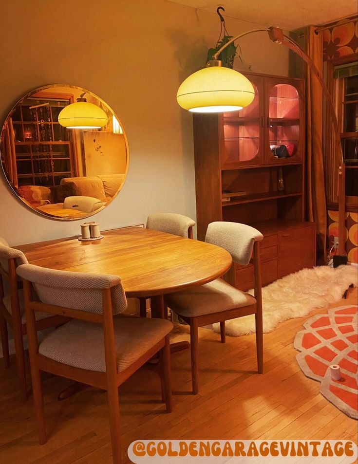 a dining room table and chairs in front of a large round mirror on the wall